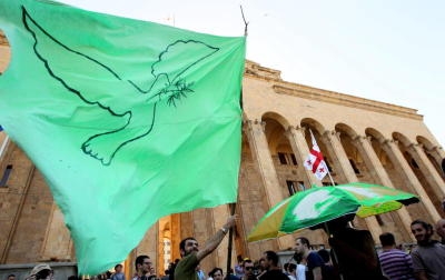 epa03727848 A protester waves a green flag depicting a peace dove with a twig of a cannabis plant in its beak during a protest rally for cannabis decriminalization in front of the former parliament building in Tbilisi, Georgia, 02 June 2013. The protest organizers said that marijuana must be singled out from the hard drugs that are considered crime and that marijuana must be decriminalized. EPA/ZURAB KURTSIKIDZE +++(c) dpa - Bildfunk+++