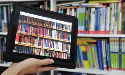 ARCHIV - ILLUSTRATION - Ein iPad Tablet mit einer Bücherwand auf dem Bildschirm, im Hintergrund ein Bücherregal (Aufnahme vom 06.10.2011). Mit dem iPad hat Apple im Jahr 2010 das E-Book-Geschäft umgekrempelt. Die damaligen Deals mit der Buchbranche sorgen aber für ein juristisches Nachspiel: Apple legt sich vor Gericht mit US-Wettbewerbshütern an. Foto: Marc Tirl dpa (zu dpa «Apple steht wegen E-Book-Absprachen vor Gericht» vom 04.06.2013) +++(c) dpa - Bildfunk+++