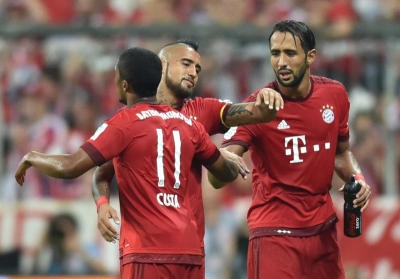 Fußball Bundesliga - 1. Spieltag: FC Bayern München - Hamburger SV am 14.08.2015 in der Allianz Arena in München (Bayern). Münchens Douglas Costa (l-r), Arturo Vidal und Mehdi Benatia jubeln nach dem Spiel. Foto: Peter Kneffel/dpa (Wichtiger Hinweis: Aufgrund der Akkreditierungsbestimmungen der DFL ist die Publikation und Weiterverwertung im Internet und in Online-Medien während des Spiels auf insgesamt fünfzehn Bilder pro Spiel begrenzt.) +++(c) dpa - Bildfunk+++