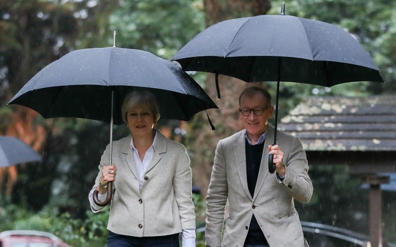 <p>23.09.2018, Großbritannien, Maidenhead: Theresa May, Premierministerin von Großbritannien, und ihr Mann Philip gehen im Regen nach einem Gottesdienst in der Nähe von Mays Wahlkreis Maidenhead. Foto: Andrew Matthews</p>